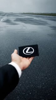 PROMPT VEO3.1: First-person POV tossing a Lexus patch on wet asphalt
