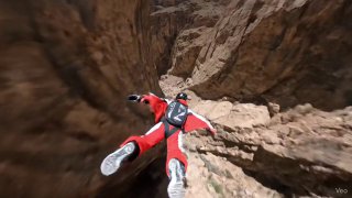 A wingsuit flyer launching off a steep mountain cliff and instantly