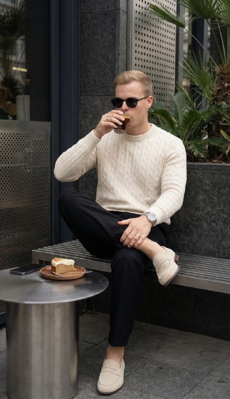 A young man sitting casually on a metal bench at a modern urban