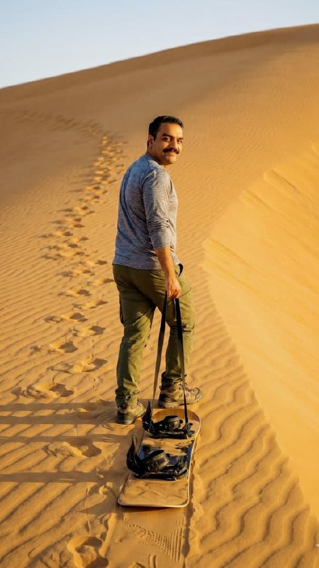 A vertical photograph of a man with a mustache hiking up a steep,